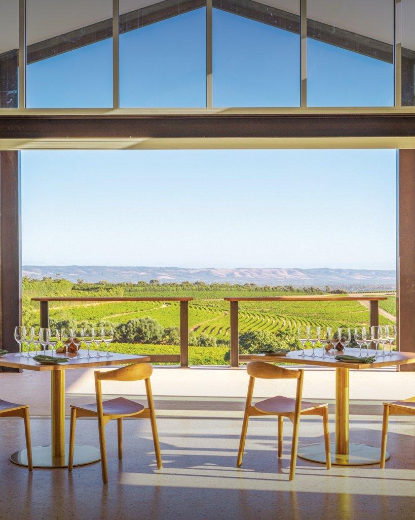 Dandelion Vineyards View from within tasting room with vines and hills in background two person table and chairs in foreground