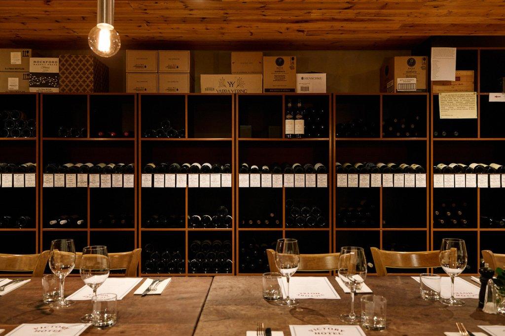 Victory Hotel Cellar with dining table set and cellar racks filled with wine in the background