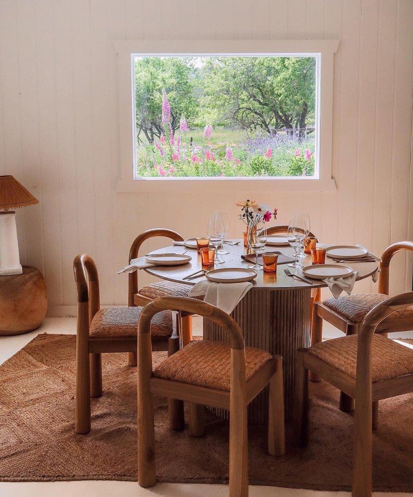 Down the Rabbit Hole resturant FIORE Dining table set in a white bright room with modern curved timber chairs with a garden view